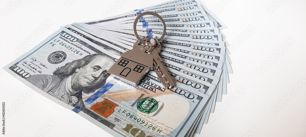 Set of house keys laying on hundred dollar bills stock photo Set of house keys laying on hundred dollar bills stock photo