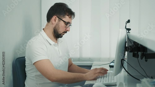 Caucasian dentist sitting at the computer at the reception and recording the patient