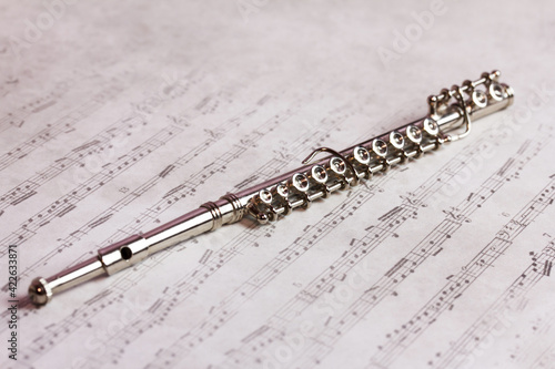 music woodwind instrument - Brass silver metal flute on a beautiful sheet music background
