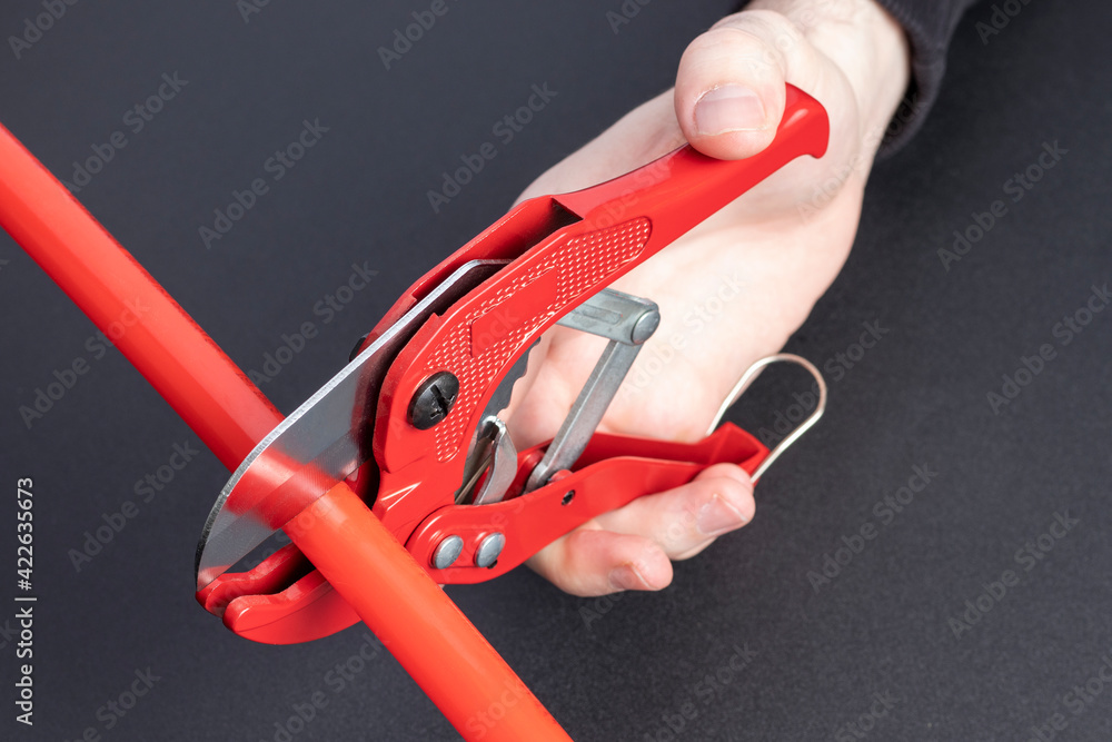 Man cuts the plastic pipe with manual pipe shears. Man cuts the plastic pipe with manual pipe shears.