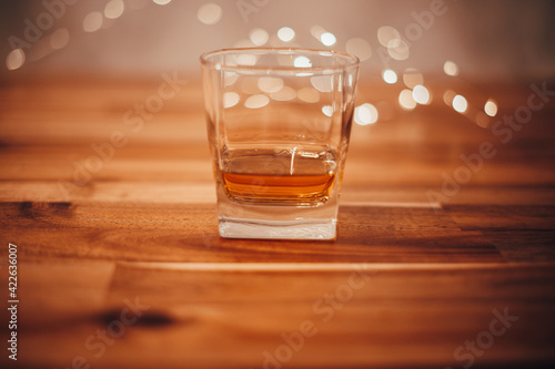 Glass voll whisky auf einem Holztisch mit Lichtern im Hintergrund. Bokeh