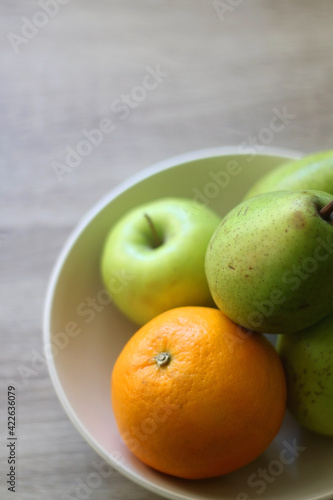 Bowl with pears, appples and oranges on a table. Selective focus.