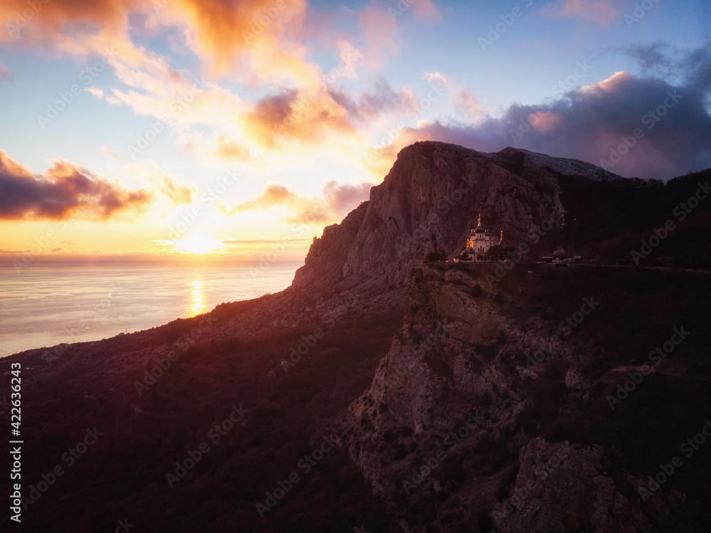 Fototapeta premium Epic high mountain church scenery aerial view. Drone epic landscape view. Colorful clouds