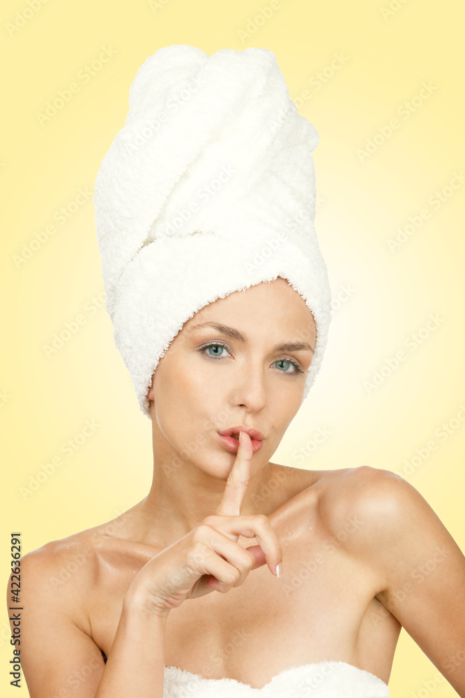 Portrait of a beautiful young woman with towel on her head showing silence gesture. Yellow background. Aesthetic concept.concept. Portrait of a beautiful young woman with towel on her head showing silence gesture. Yellow background. Aesthetic concept.concept.