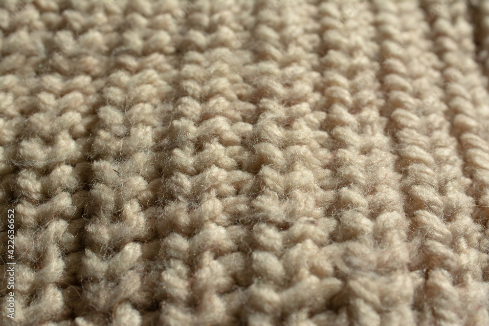 Close-up of a large knitted jumper. English knit. Beige, natural colour. Close-up of a large knitted jumper. English knit. Beige, natural colour.