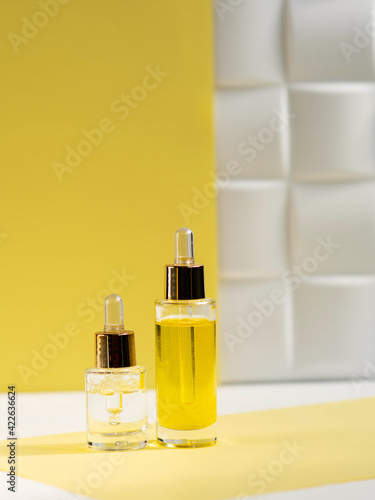 cosmetic serum and natural cosmetic oil in glass bottles on a yellow background. Skin beauty and health concept.
