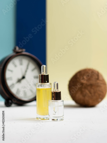 Coconut oil skin care serum with coconut on blue background. Skin beauty and health concept.
