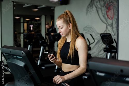 Happy athletic woman jogging on treadmills in a gym.