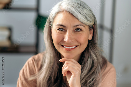 Close-up portrait of a beautiful successful mature asian business woman, self-confident gray haired lady in casual stylish wear, looking directly at the camera with friendly smile