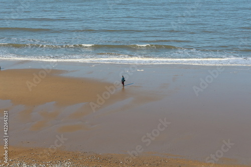 Cromer, Nortfolk, man walking on the beach, winter, seaside gentle waves crashing on the shore, north sea, seascape, northern Europe