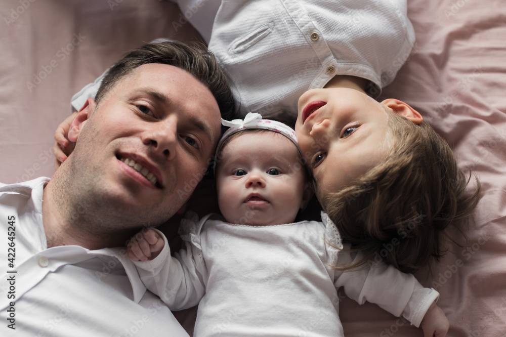 Dad with kids lying on the bed. Dad, son and baby daughter. Close up.