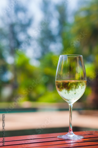 A glass of white wine on a tropical background.