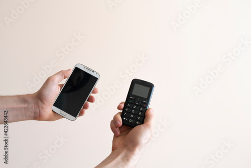 Wallpaper Mural person hands holding two cell phones, vintage old and modern new, era difference Torontodigital.ca