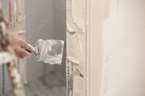 Builder using a trowel to add plaster. Plastering wall with putty-knife, close up image. Fixing wall surface and preparation for painting. construction work during quarantine