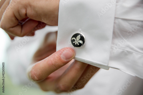 Bild auf Leinwand Closeup shot of a groom's hand fixing the cufflinks of his white shirt before th