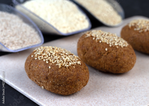A healthy gluten-free keto bread made from almond flour and psyllium husk, sprinkled with sesame seeds. Baking ingredients in scoops. Ketogenic diet, paleo, low carb, high fat.