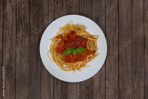 Pasta with rustic tomato sauce and basil leaves. Served on the white plate. Top view photography with centralized elements. Italian Gastronomic Photo.