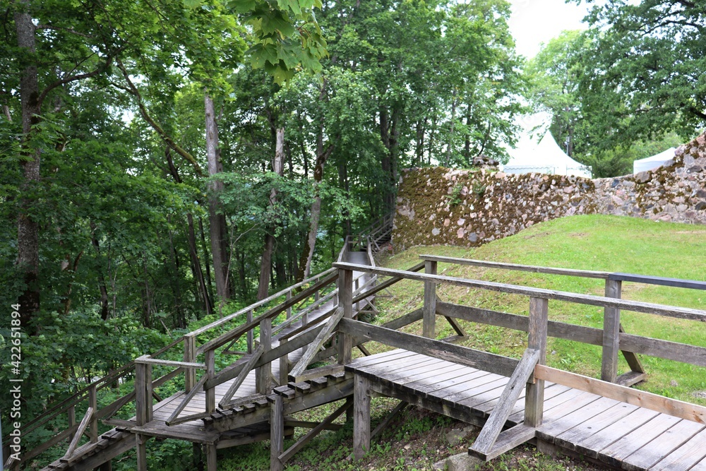 Staircase made of thick wooden planks on a hillside near a stone wall Staircase made of thick wooden planks on a hillside near a stone wall