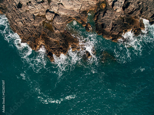 A drone shot of a beautiful rocky beach with clear turquoise sea water.