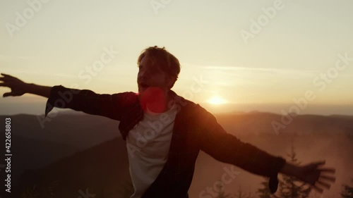 Man dancing in mountains at sunset. Happy guy gesturing hands during dance photo