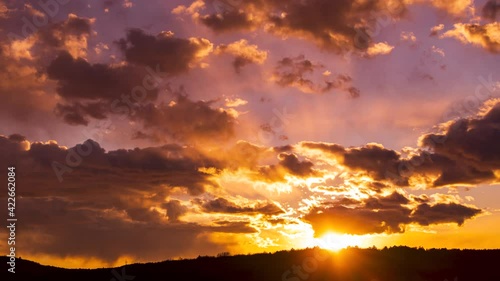 Sun shines through clouds above mountains valley, golden hour sunset sky sihlouette timelaps background laps 4K