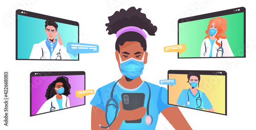 african american doctor in mask discussing with mix race colleagues during video call online consultation