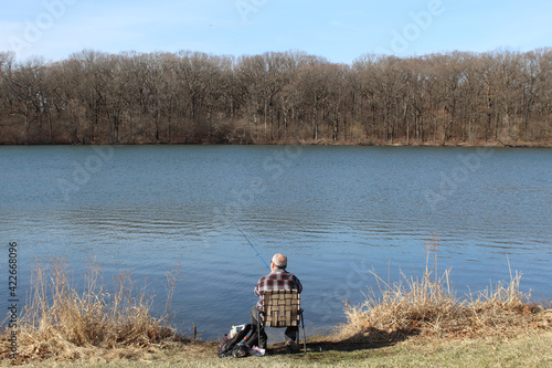 Man in a flannel shirt fishing at Horsetail Lake in Palos Park, Illinois
