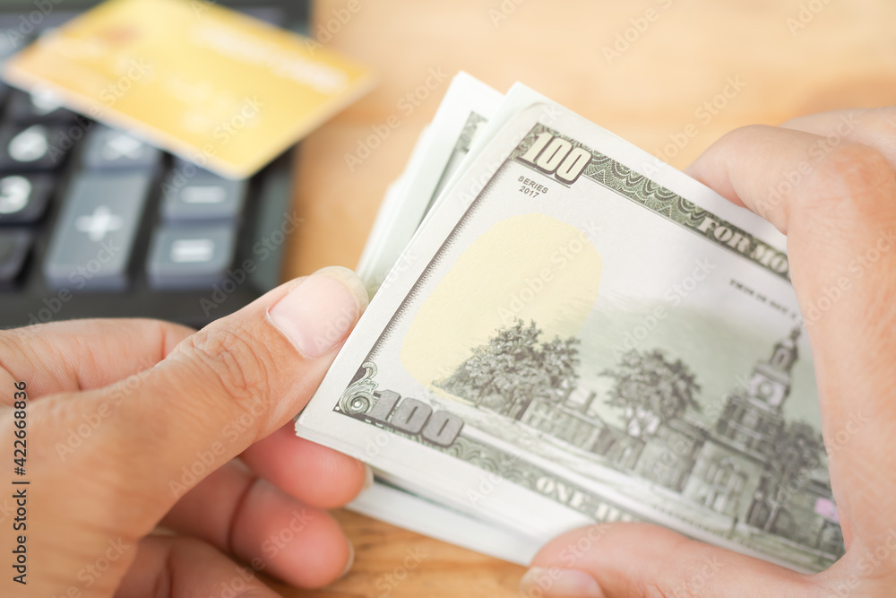 100 dollars. Close up hand woman counting money bank note with credit card and calculator blured. planing earn money investment and saving money future for 2022 new year. finance and business concept. 100 dollars. Close up hand woman counting money bank note with credit card and calculator blured. planing earn money investment and saving money future for 2022 new year. finance and business concept.