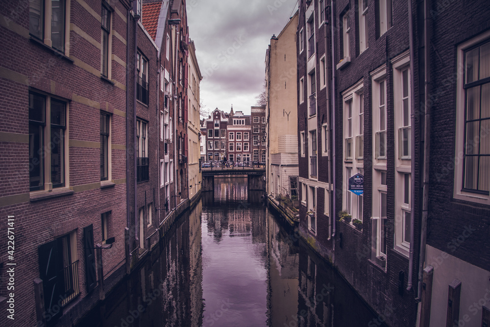 alley with a narrow canal in the city of amsterdam