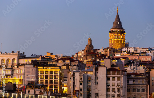 Picturesque view of lighted Galata Tower topping over residential buildings of Beyoglu district in Istanbul in winter evening.