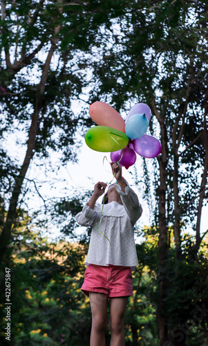 Happy child girl playing with colorful toy balloons in the park outdoors. © banphote