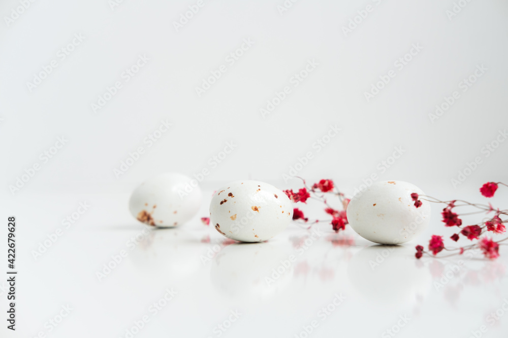 Easter minimal composition with eggs and flowers on the white background. Easter concept. Copy space.