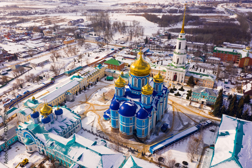 View from drone of Zadonsk Monastery of Nativity of Virgin with golden domes of St. Vladimir Cathedral and St. Nicholas of Myra Church belfry on winter day, Russia