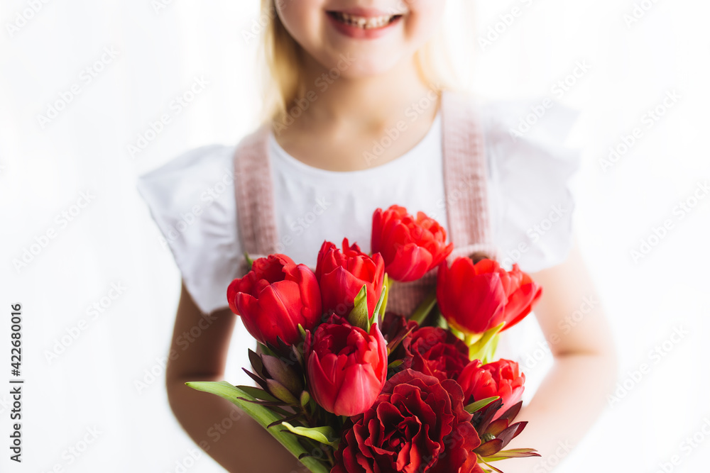 Smiling small girl holding bouquet of red tulips. Concept for greeting card
