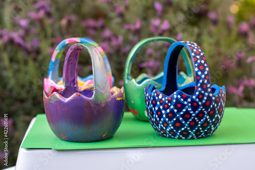 Hand-painted Easter egg baskets on a green pedastal in front of purple lavender flowers. photo