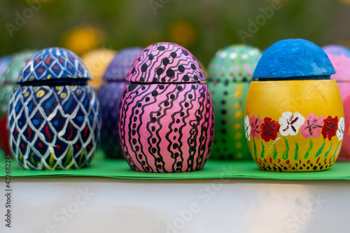 Hand-made Easter eggs on a green pedastal in front of yellow and orange spring flowers photo