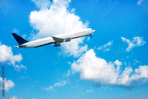 A big white jet flying on background of blue cloudy sky.