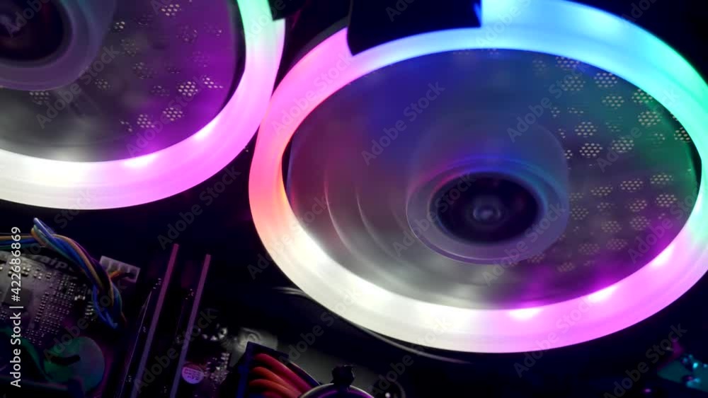 Cooling fans illuminated by LEDs inside personal computer. Powerful desktop gaming PC with multicolored RGB lights. Streaming studio is equipped with professional setup Cooling fans illuminated by LEDs inside personal computer. Powerful desktop gaming PC with multicolored RGB lights. Streaming studio is equipped with professional setup