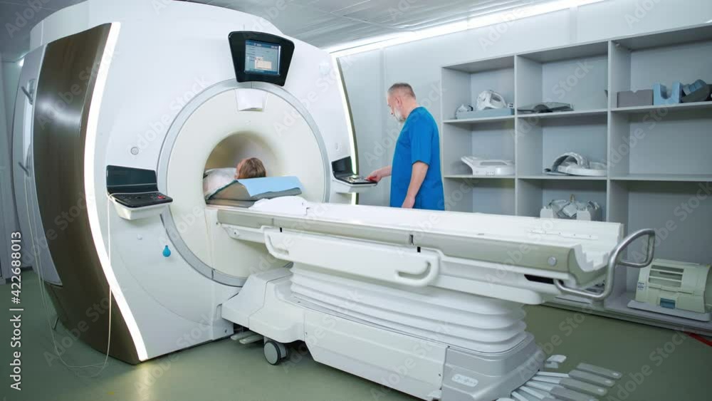 Magnetic resonance imaging in the modern hospital, adult man doctor performs a magnetic tomographic examination of a young woman, MRI, modern technologies in medicine. Magnetic resonance imaging in the modern hospital, adult man doctor performs a magnetic tomographic examination of a young woman, MRI, modern technologies in medicine.