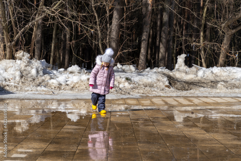 happy funny child girl looks at her reflection in the spring puddles and smile happy funny child girl looks at her reflection in the spring puddles and smile