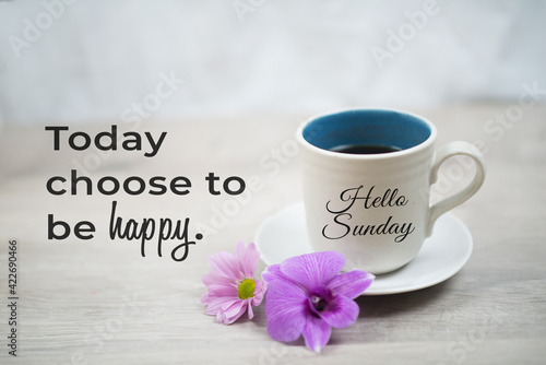 Sunday inspirational quote -  Today choose to be happy.  With hello Sunday greeting on cup of morning coffee and purple orchid daisy flowers on white table background. Happy Sunday weekend concept. photo