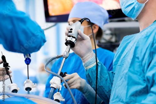 Selective focus on the hand of a surgeon wearing a sterile latex glove holding a special medical instrument during laparoscopic surgery. Minimally invasive surgical treatment of proctological diseases