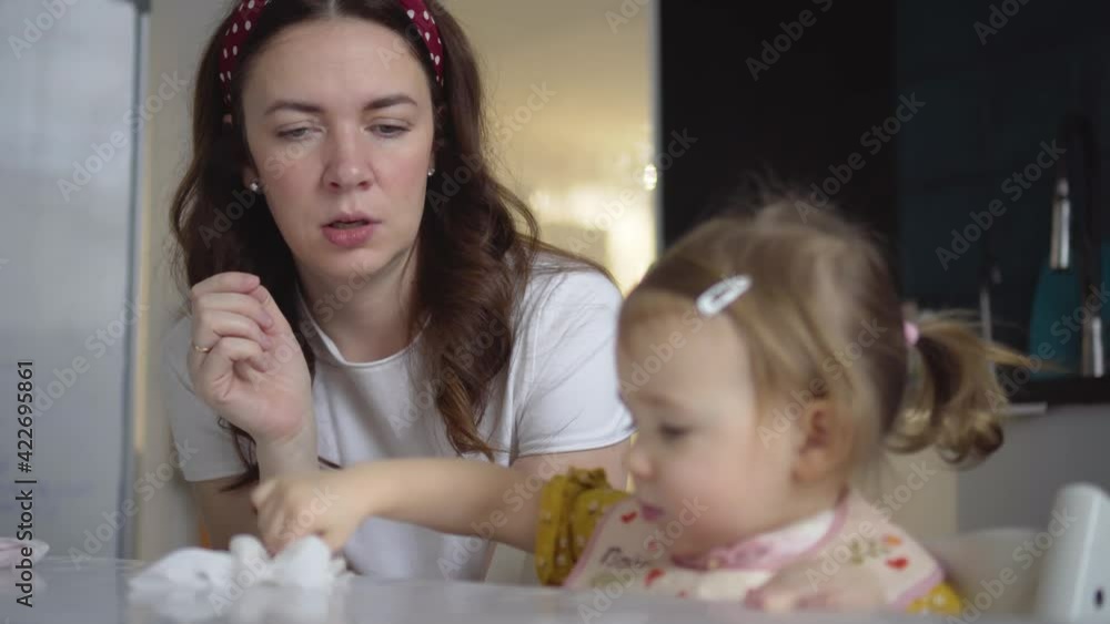 Cute child eating. Baby girl eating healthy food herself. Mom feeds her little daughter Cute child eating. Baby girl eating healthy food herself. Mom feeds her little daughter