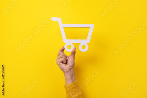shopping cart symbol in hand over yellow background photo