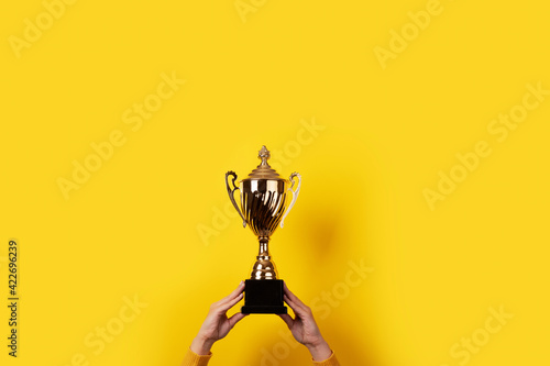 woman holding up a gold trophy cup as a winner in a competition