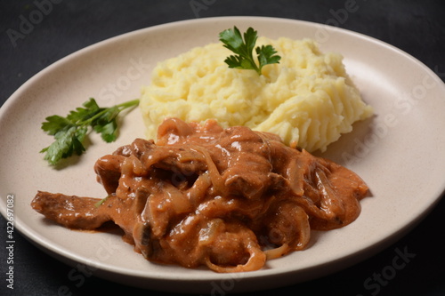 Traditional beef stroganoff in a ceramic white plate with mashed potatoes