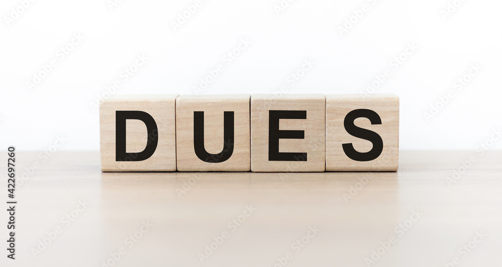text dues on wooden cubes on light wooden table isolated text dues on wooden cubes on light wooden table isolated