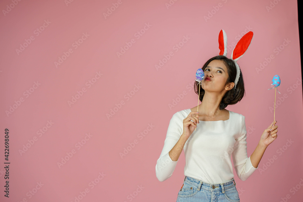 Mixed race young beautiful woman smiling and standing with Easter egg t celebrate traditional Christian festival standing on Pink background