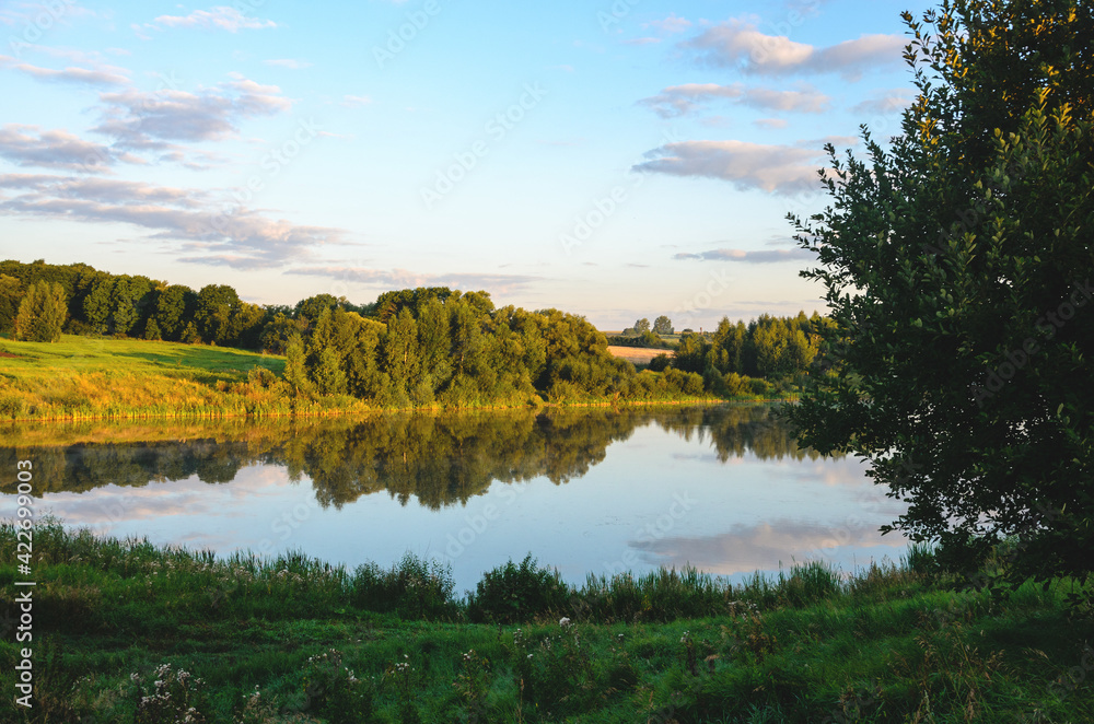 Summer serene landscape with calm river and green hills at sunrise. Summer serene landscape with calm river and green hills at sunrise.