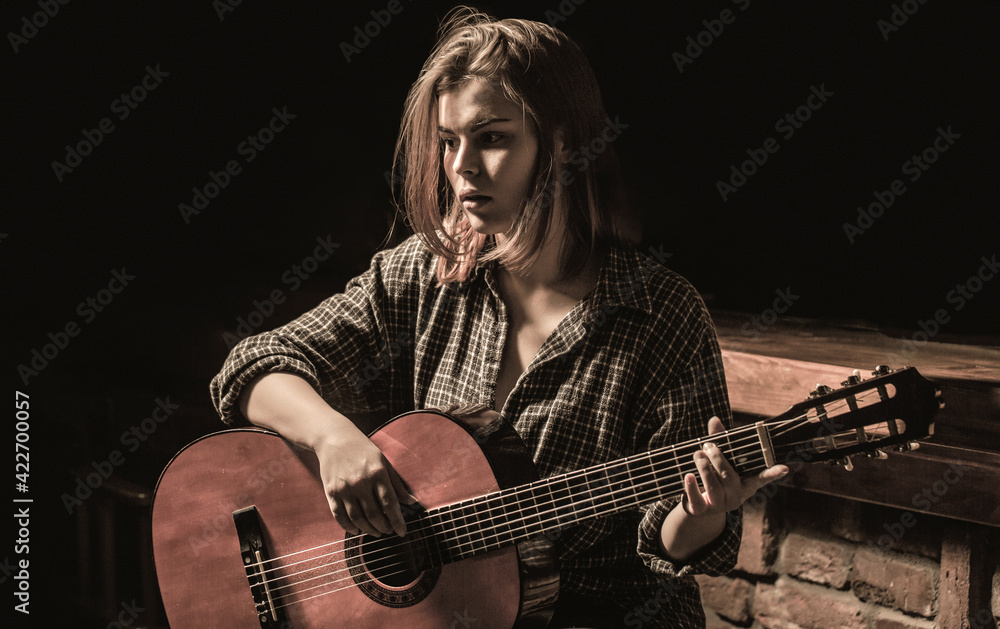 Obraz premium Woman playing guitar, holding an acoustic guitar in his hands. Music concept. Girl guitarist plays. Girl play the guitar. Woman hipster man sitting in a pub